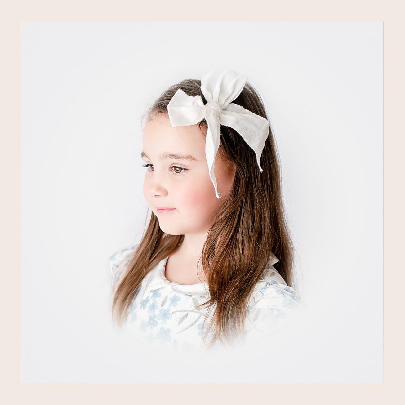 Young girl with white bow headband in heirloom-style studio portrait